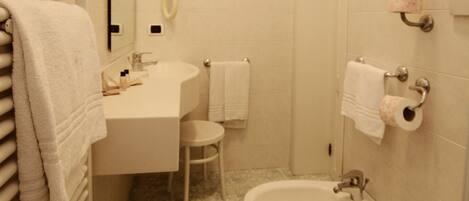 Un baño con lavamanos, bidé, inodoro y espejo.