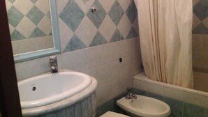 A bathroom with a sink, bidet, and toilet.