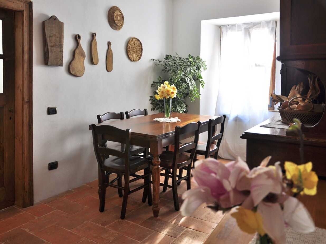 Een eetgedeelte met een houten tafel en stoelen, omringd door wanden met gevlochten manden en een potplant.