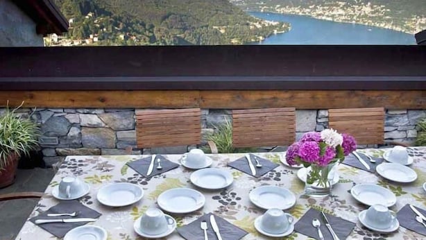 Une table dressée pour le dîner, avec vue sur un lac et des montagnes.