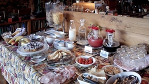 Une table de buffet proposant une variété de plats, notamment des viandes, des fromages et des fruits, ainsi que des condiments et des boissons.
