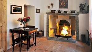 Une pièce chaleureuse avec une cheminée, une table à manger avec des chaises et un vase de fleurs.