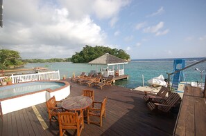 A wooden deck with a hot tub, lounge chairs, and a gazebo overlooking a body of water. - San Bar 6BR by Jamaican Treasures (Port Antonio)