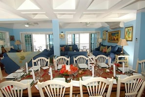 A dining area with white chairs, a wooden table set for a meal, and a blue sofa in the background.
