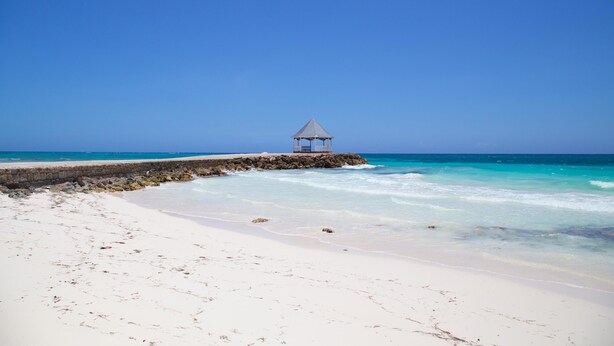 A beach with a small gazebo-like structure on a rocky outcrop.