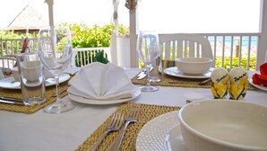 A table set for dining with white tableware, including plates, glasses, and cutlery, on a woven placemat.