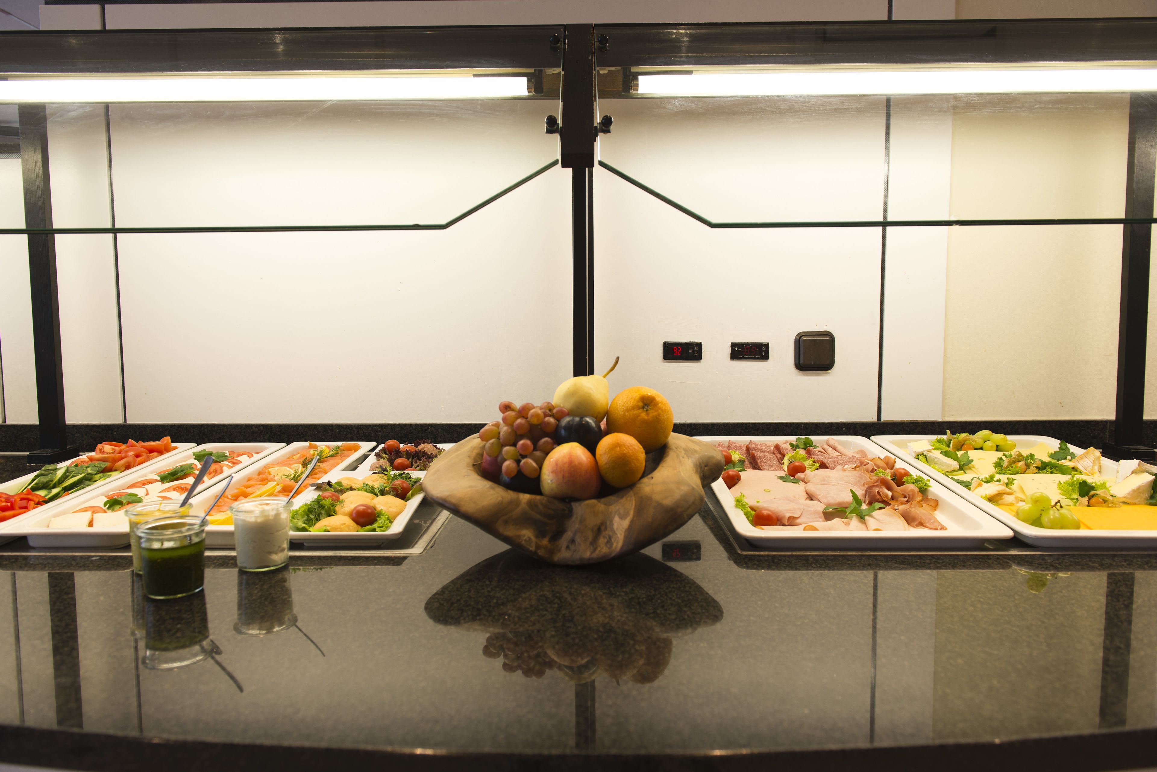 A buffet table with various food items and a central fruit bowl.