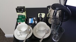 A breakfast tray with tea, coffee, and hot chocolate packets, along with two cups and a kettle. - The Oxford House (Oxford)