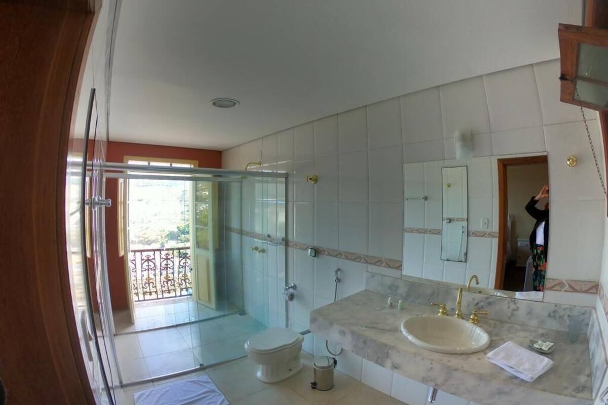 Ein Badezimmer mit einem großen Spiegel, einem Waschbecken und einer Toilette.