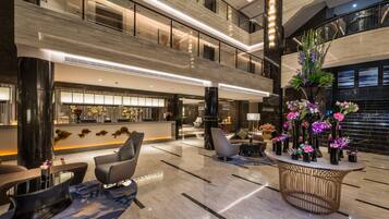 A spacious lobby with a high ceiling, multiple seating areas, and a reception desk.