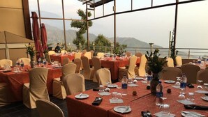 Un salón de banquetes con mesas dispuestas para un evento formal, con vistas panorámicas a la montaña a través de amplios ventanales.