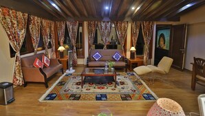 Una sala de estar con un sofá, sillones, una mesa de centro y una alfombra estampada.