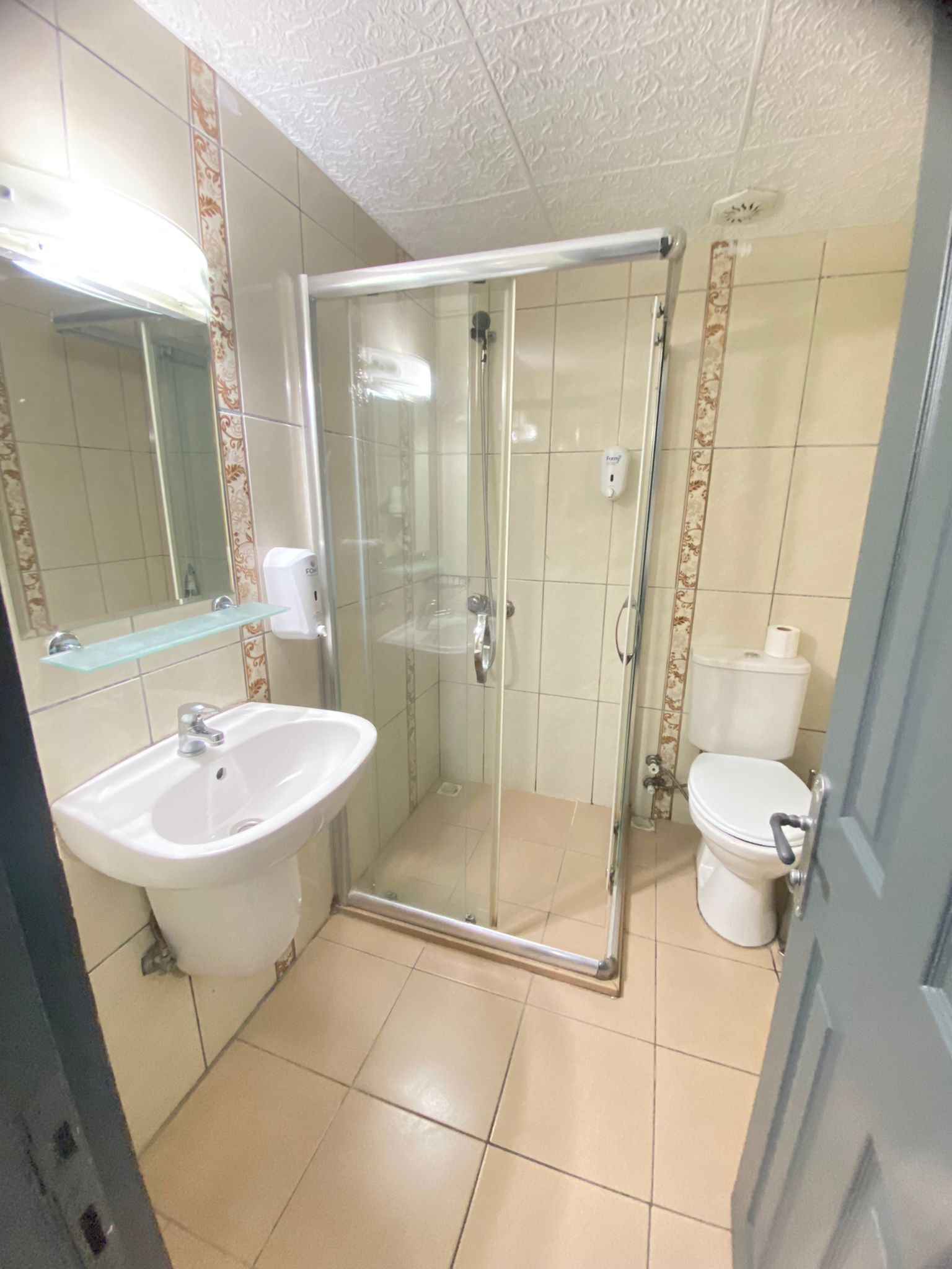 Une salle de bain avec une douche à parois de verre, un lavabo et des toilettes.