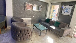 A modern living room with a grey sofa, a tufted armchair, and a glass coffee table. - Abam Hotel (Istanbul)