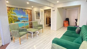 A spacious living area with a green sofa, a green armchair, and a small table. There is a mural of a tropical scene on the wall. - Abam Hotel (Istanbul)