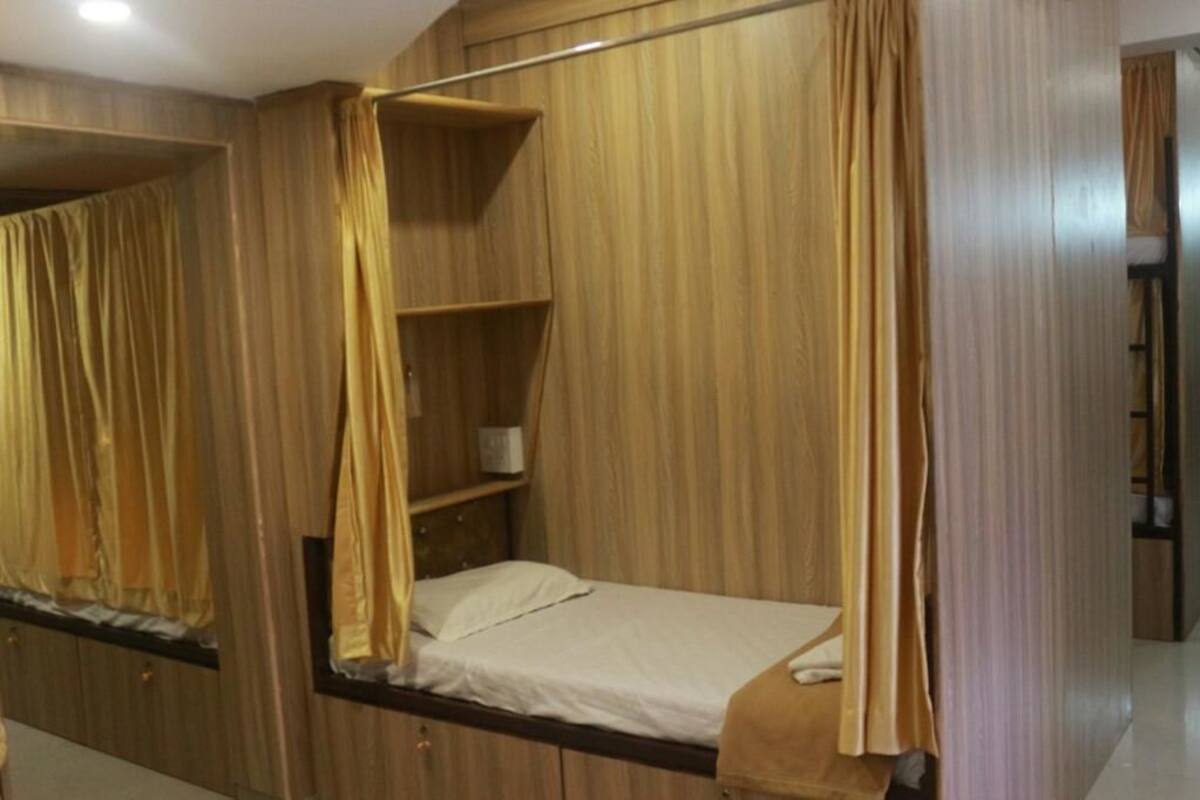 A single bed with a wooden headboard and a shelf above it.