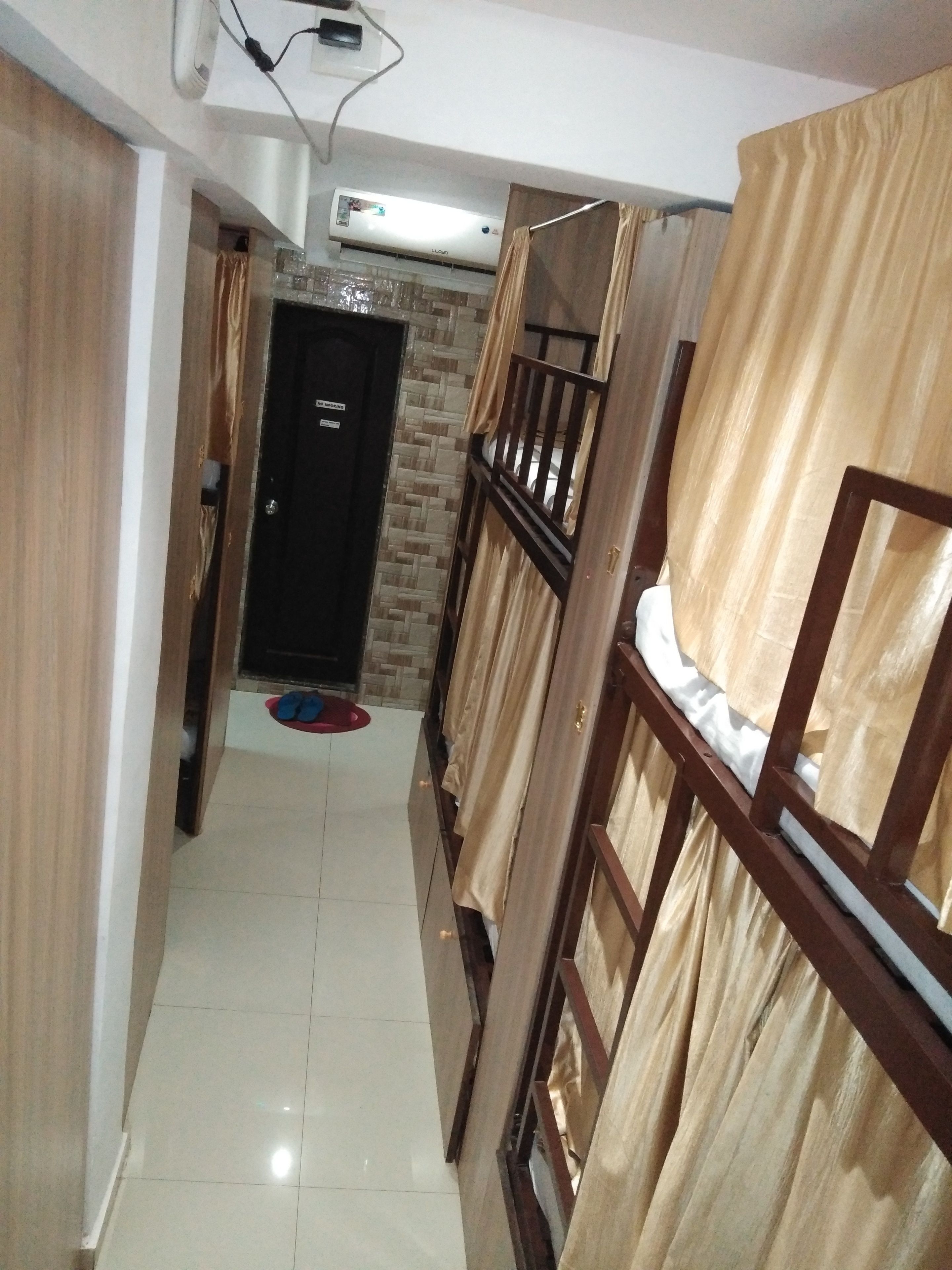 A narrow hallway with bunk beds, a tiled floor, and a door at the end.