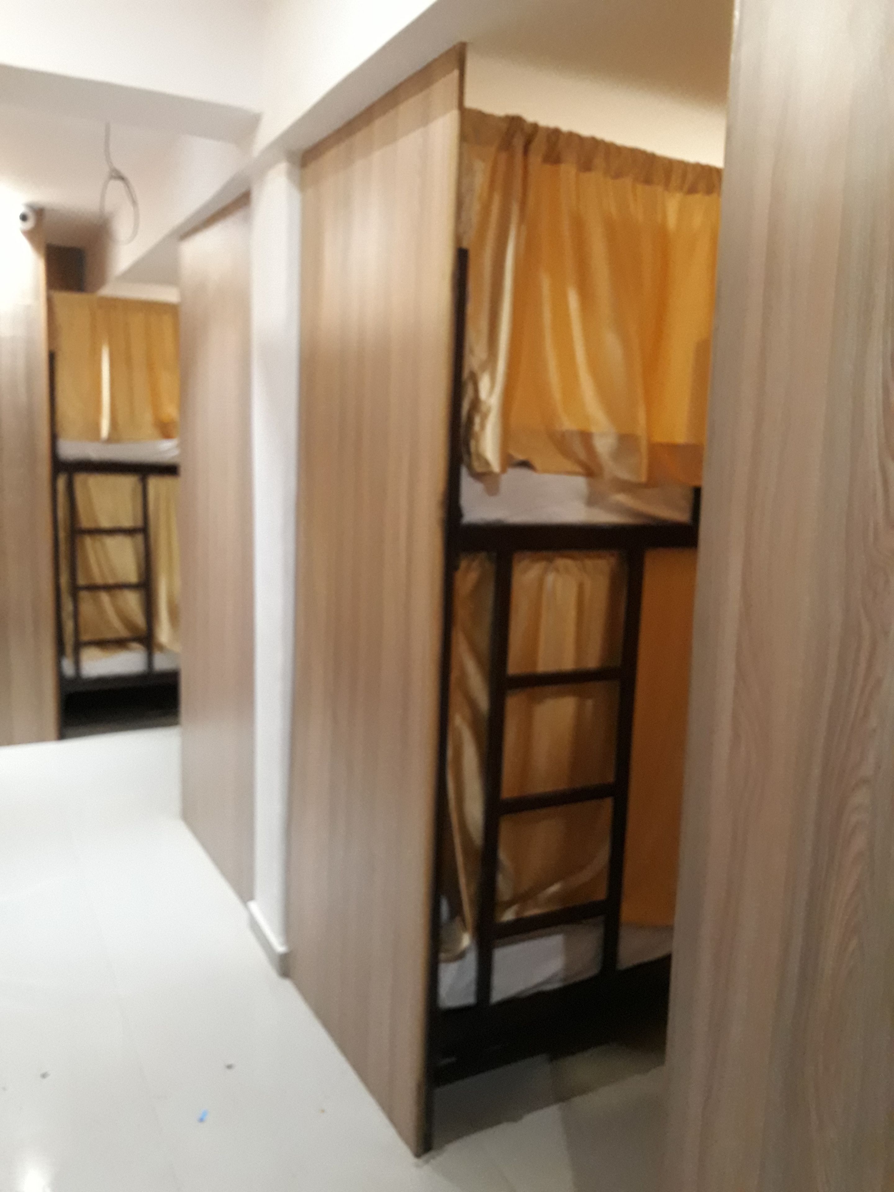 A corridor with bunk beds, wooden walls, and a white floor.