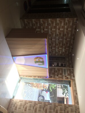 Zona de recepción con mostrador de madera, pared de azulejos y vista al exterior.