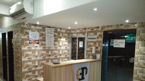 A reception desk with a patterned wall, a glass door, and a sign indicating a check-in time of 12:00 PM. - Golden Dormitory - Hostel (Mumbai)