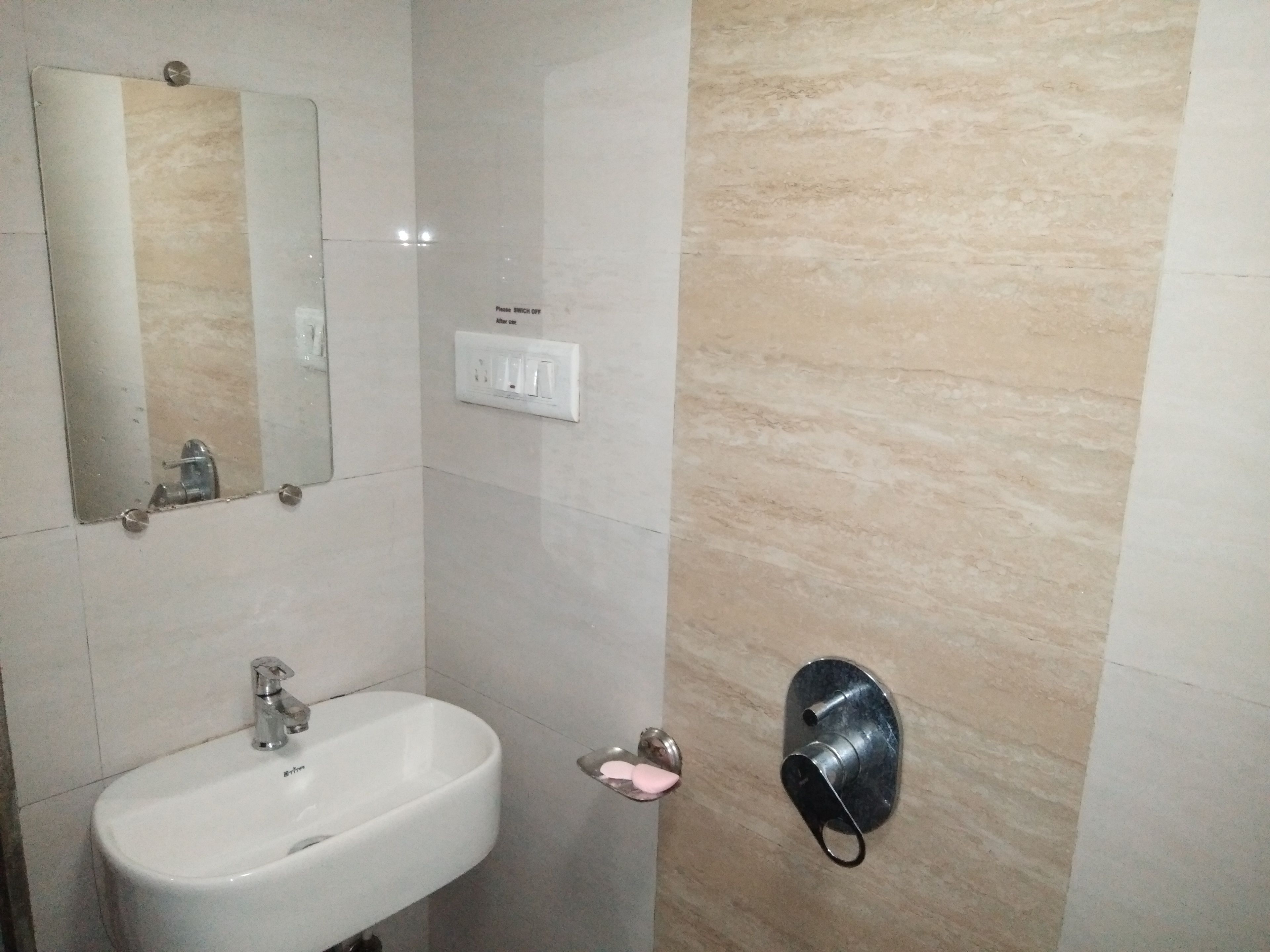 Een badkamer met een wit wastafel, een spiegel, een handdoekhouder en een zeepdispenser.