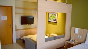 Una habitació d'hotel amb un llit, una taula de nit, una televisió i un quadre a la paret.