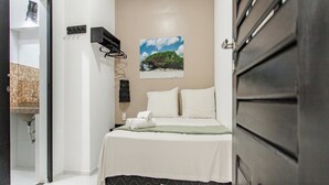 Un dormitorio con una cama, un estante en la pared, un cuadro y una puerta.