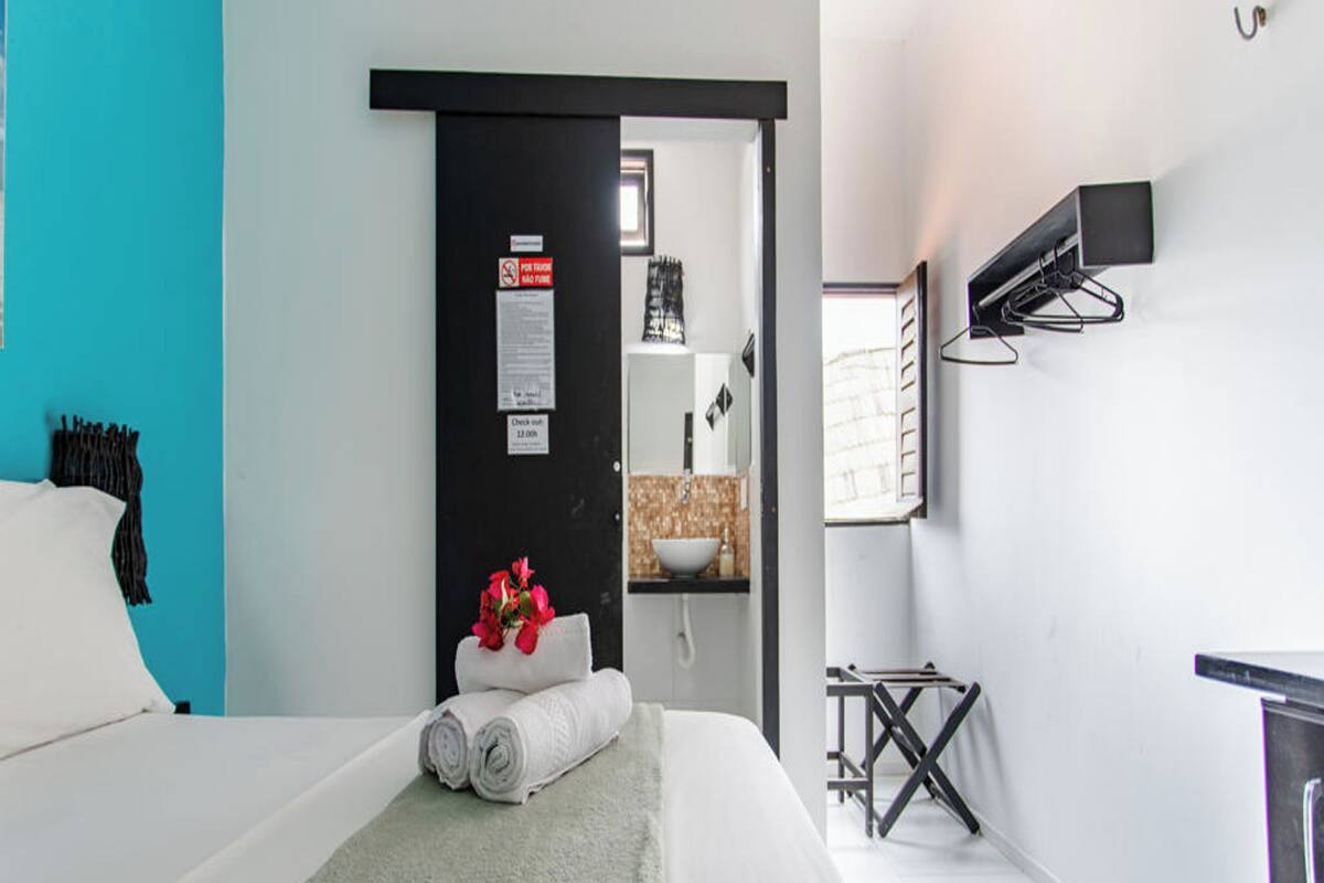 A modern hotel room with a bed, a desk, and a bathroom.