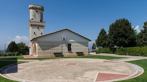 A building with a tower, a paved courtyard, and surrounding greenery. - La Vecchia Torre (San Nicola Manfredi)