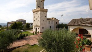 A tower with a crenellated top, a building with a tiled roof, and a clear sky. - La Vecchia Torre (San Nicola Manfredi)