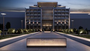 A modern hotel entrance with a central entrance, symmetrical design, and a well-lit pathway leading to the doors. - La Réserve (Knokke-Heist)