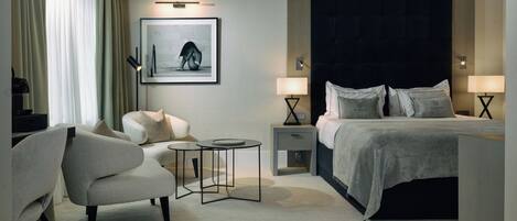 Una habitación de hotel moderna con una cama, un sofá, una mesita y una mesita de noche con lámparas.