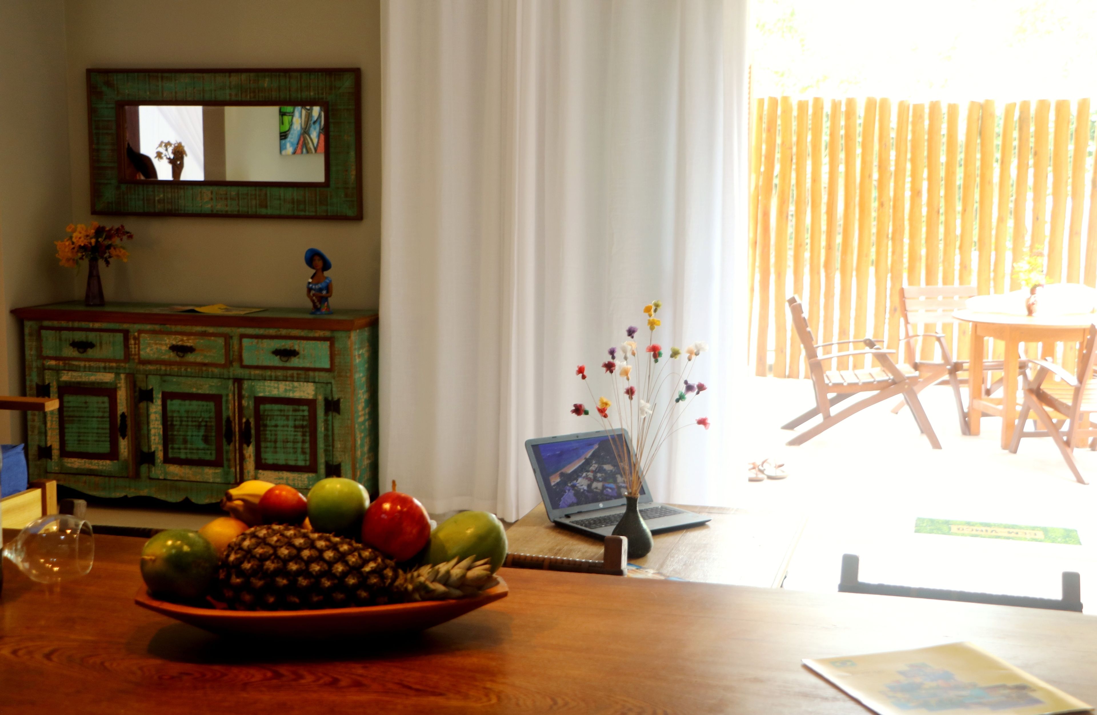 Uma área de refeições com uma mesa de madeira, um laptop e um vaso com flores.