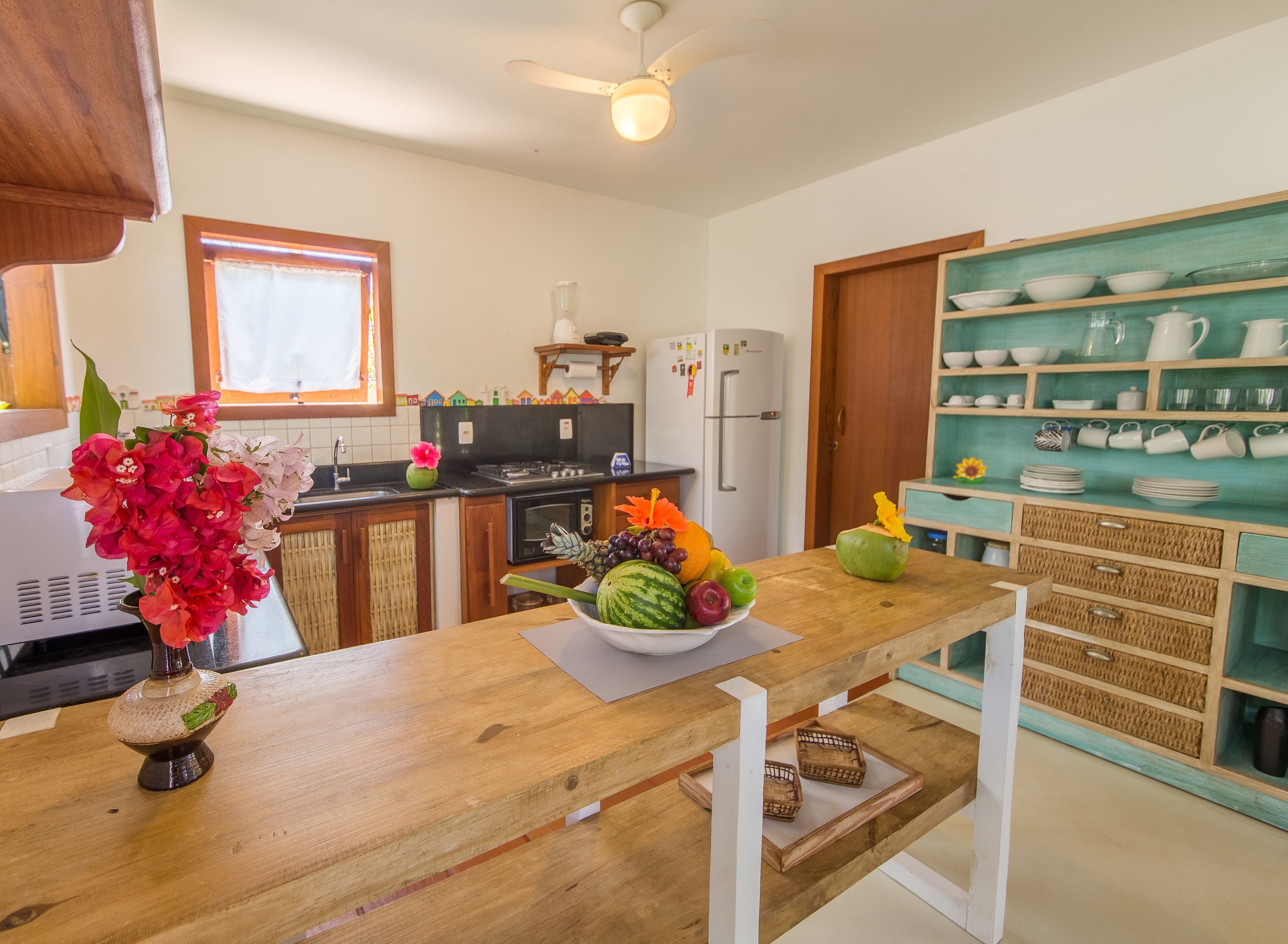 A kitchen with a wooden countertop, a fruit bowl, and a refrigerator.