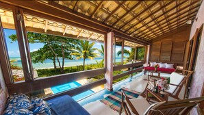 A room with a view of the beach, a pool, and a seating area with a sofa and chairs. - Residence Pé na Areia (Porto Seguro)