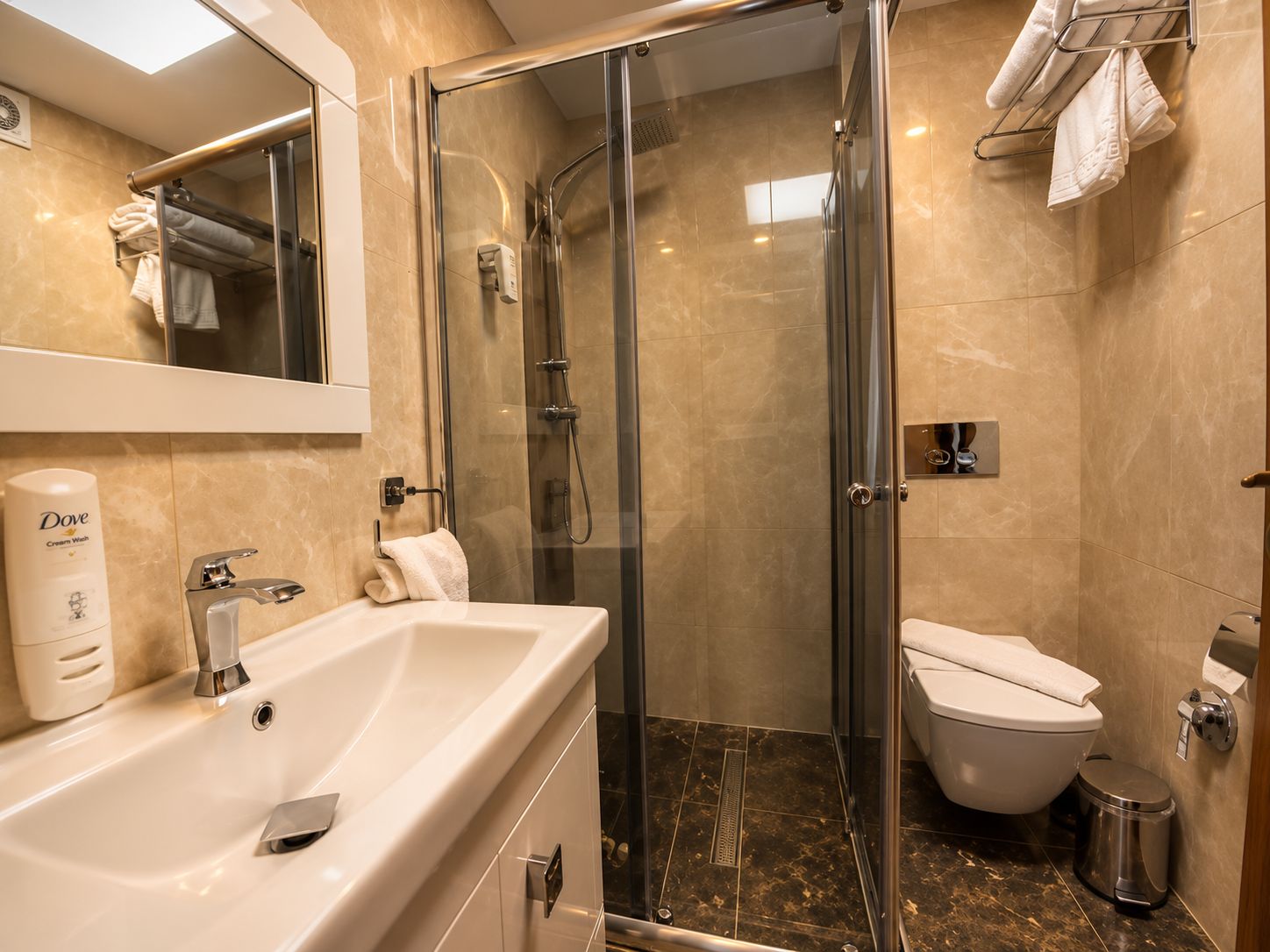 A modern bathroom with a glass-enclosed shower, a white sink, and a toilet.