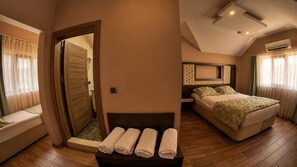 A hotel room with a bed, a sofa, a small table with towels, and a shower area. - Senler Butik Otel (Sapanca)