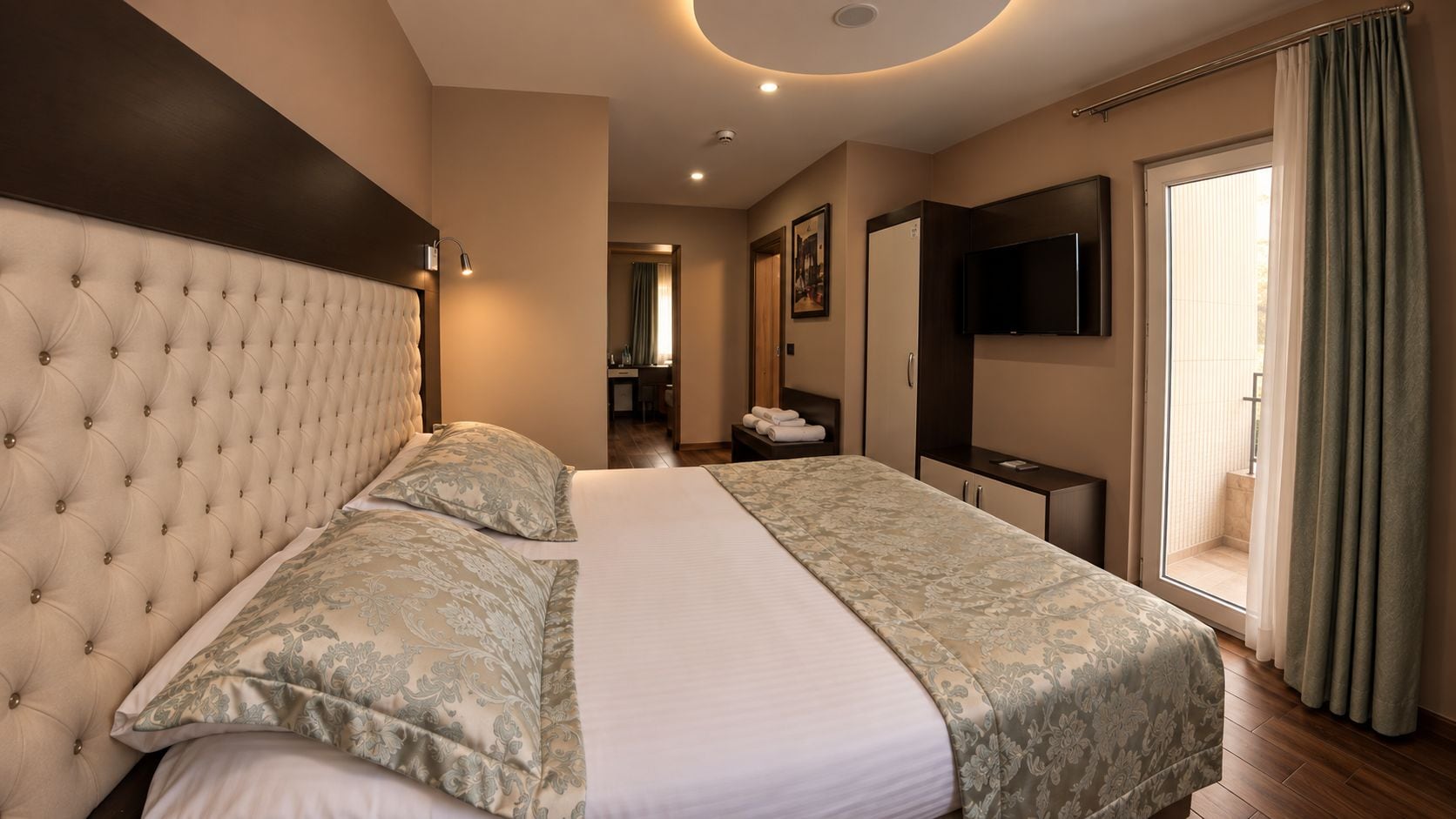 A hotel room with a large bed, a flat-screen TV, and a bathroom visible through an open door.