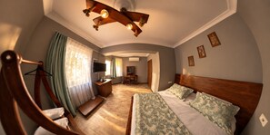 A hotel room with a bed, a wooden headboard, a desk with a chair, a television, and a window with curtains. - Senler Butik Otel (Sapanca)