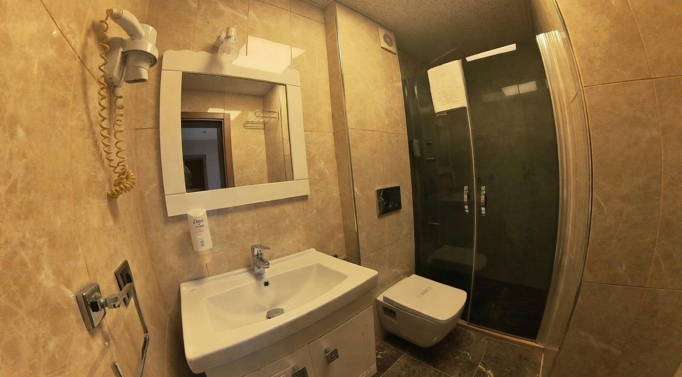 A bathroom with a sink, mirror, and shower.