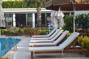 A poolside area with lounge chairs, a palm tree, and outdoor furniture. - Senler Butik Otel (Sapanca)