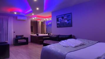 A modern hotel room with a bed, a seating area, a vanity, and a large mirror.