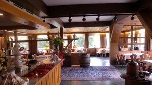 Un amplio vestíbulo de hotel con una zona de bar central, diferentes disposiciones de asientos y grandes ventanales que ofrecen luz natural.
