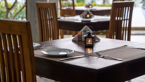 A dining table set with plates, cutlery, and a lantern. - Ananya Beach Resort (Rekawa)