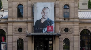 A building facade with a large poster advertising an event.