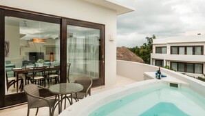 A modern outdoor pool area with a glass door leading to a dining space, a hot tub, and a view of neighboring buildings. - Mak Nuk Village Tulum II - Clothing Optional (Tulum)