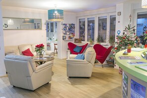 A modern living room with two beige sofas, a red armchair, a coffee table, and a Christmas tree. - The Dots Hostel (Zagreb)