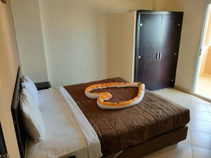 A single bed with a brown cover, a white pillow, and a decorative orange and white pet bed on the bed.