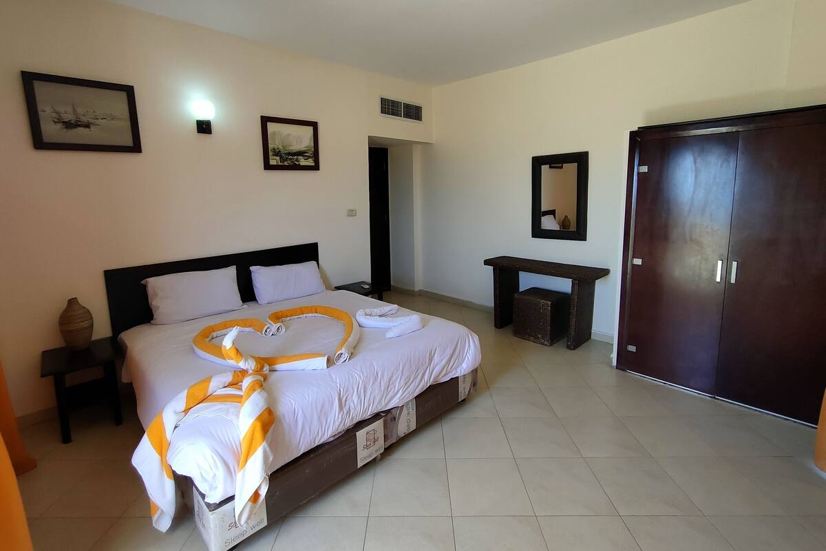 Ein Hotelzimmer mit Bett, Nachttisch, Schrank und Spiegel an der Wand.