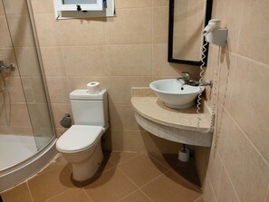 A bathroom with a toilet, sink, and shower.